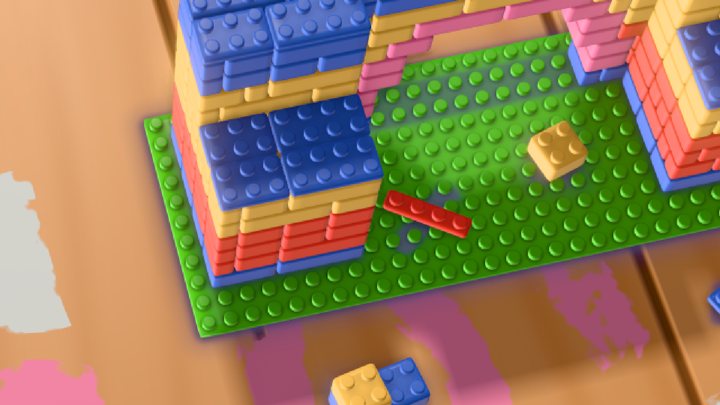 Close-up of a toy brick building on a green baseplate beside the track